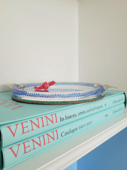 detail of an Italian mirror tray with twisted blue Murano glass frame on a stack of Venini books