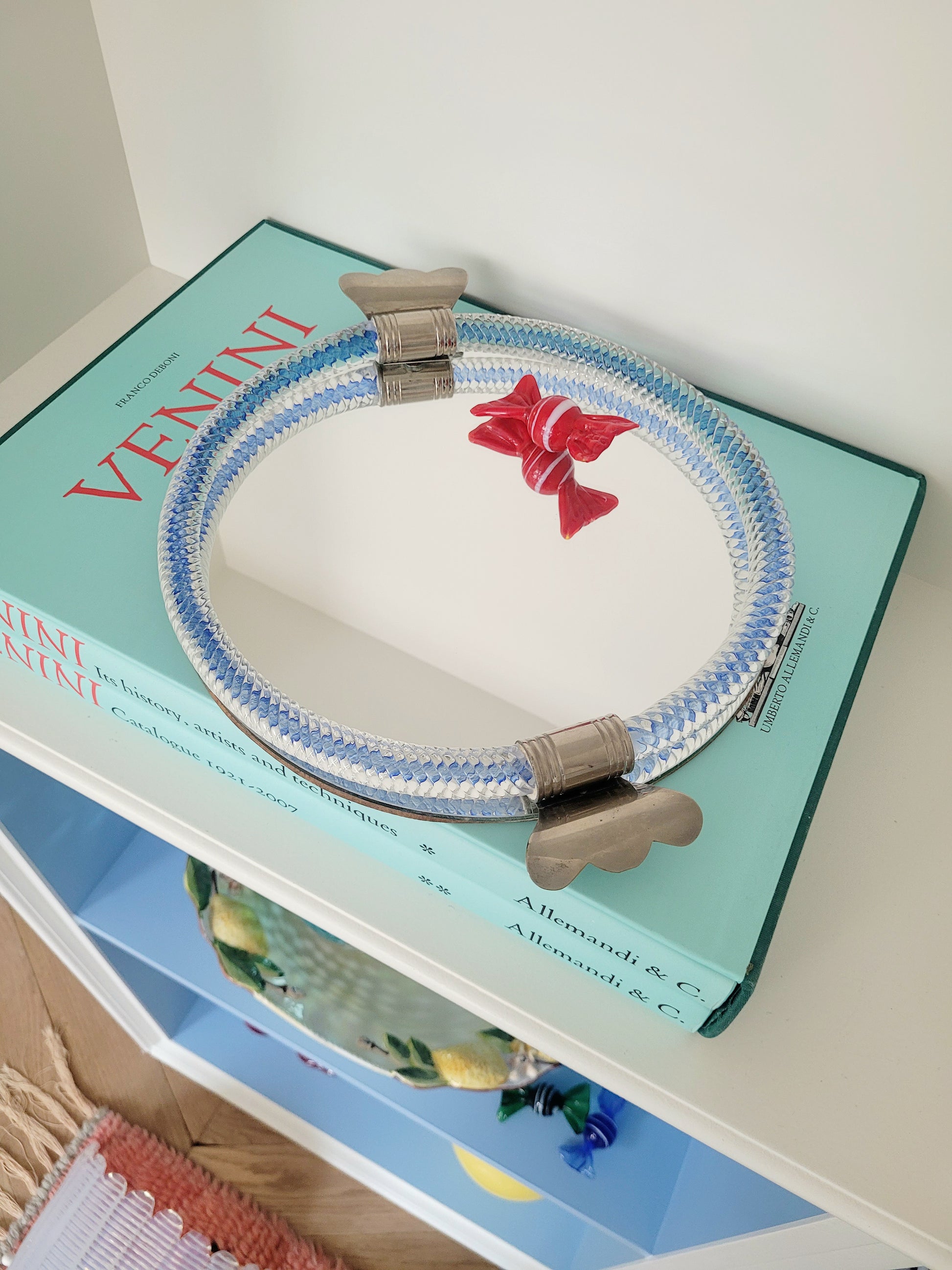 side view of an Italian mirror tray with twisted blue Murano glass frame on a stack of Venini books
