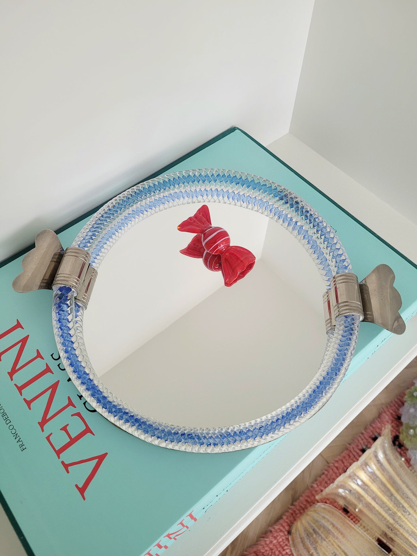 full view of an Italian mirror tray with twisted blue Murano glass frame on a stack of Venini books