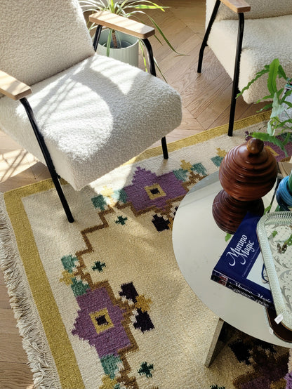 A large flatweave rug in a stunning warm colour palette that incorporates yellow, purple and green