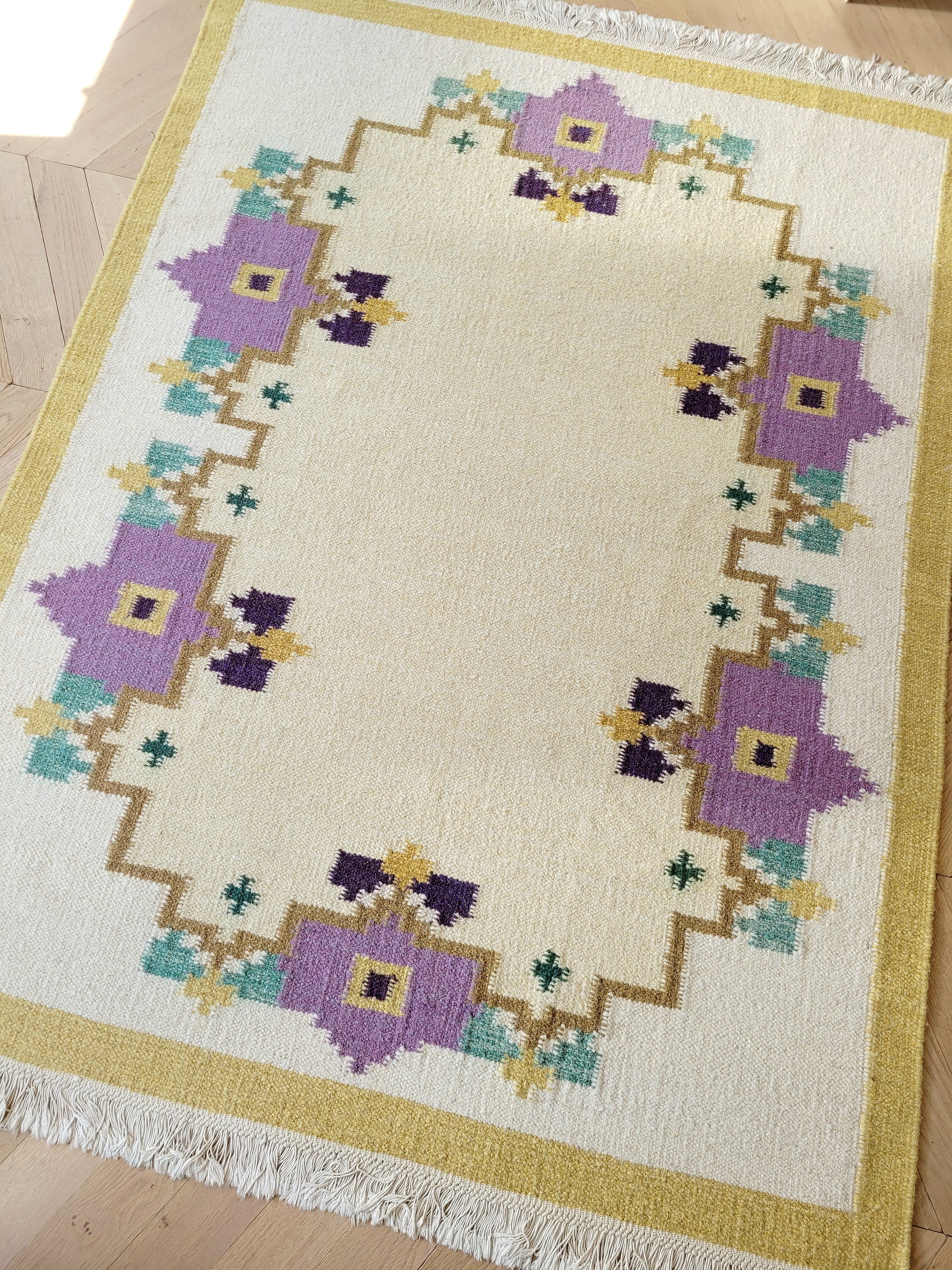 A large flatweave rug in a stunning warm colour palette that incorporates yellow, purple and green