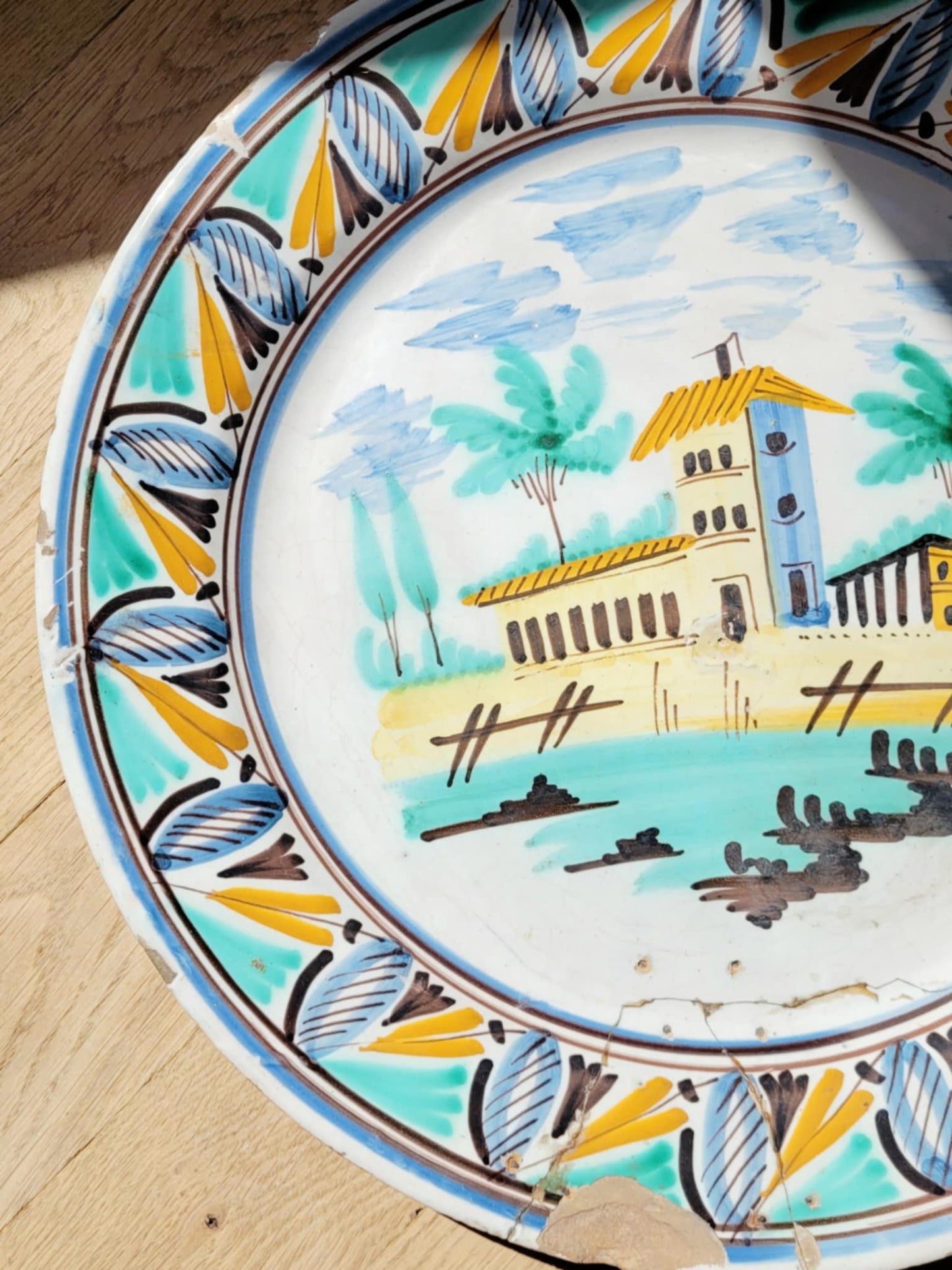 detail of a large hand-painted wall plate with rural landscape on a parquet 