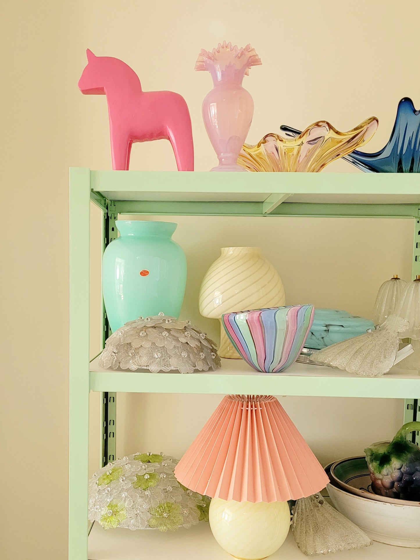 full view of a large pink wooden Dala horse on a shelf with other vintage glass items
