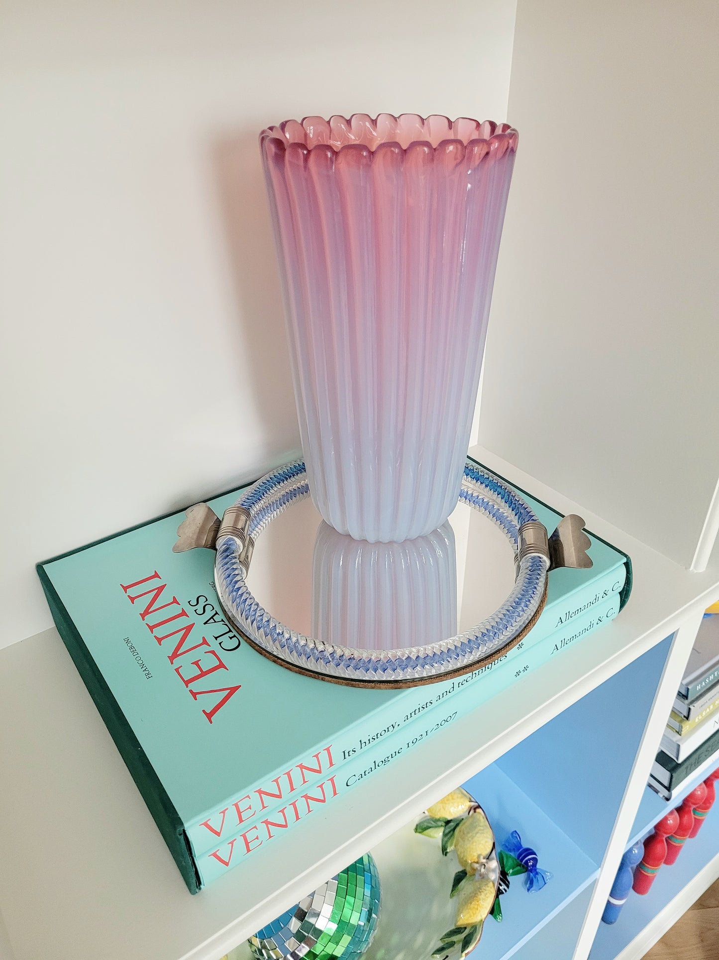 a large vintage pink ribbed Murano vase on a vintage Murano mirror tray and a stack of Venini books