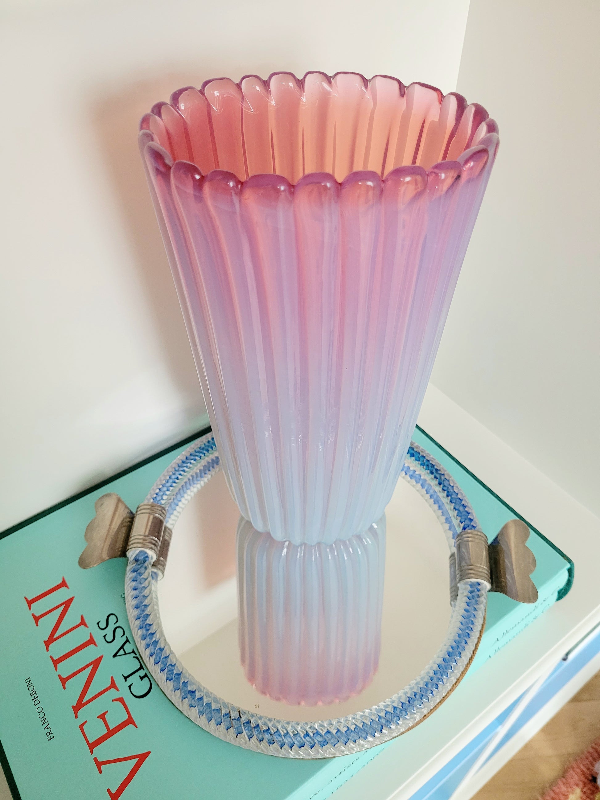 a large vintage pink ribbed Murano vase on a vintage Murano mirror tray and a stack of Venini books