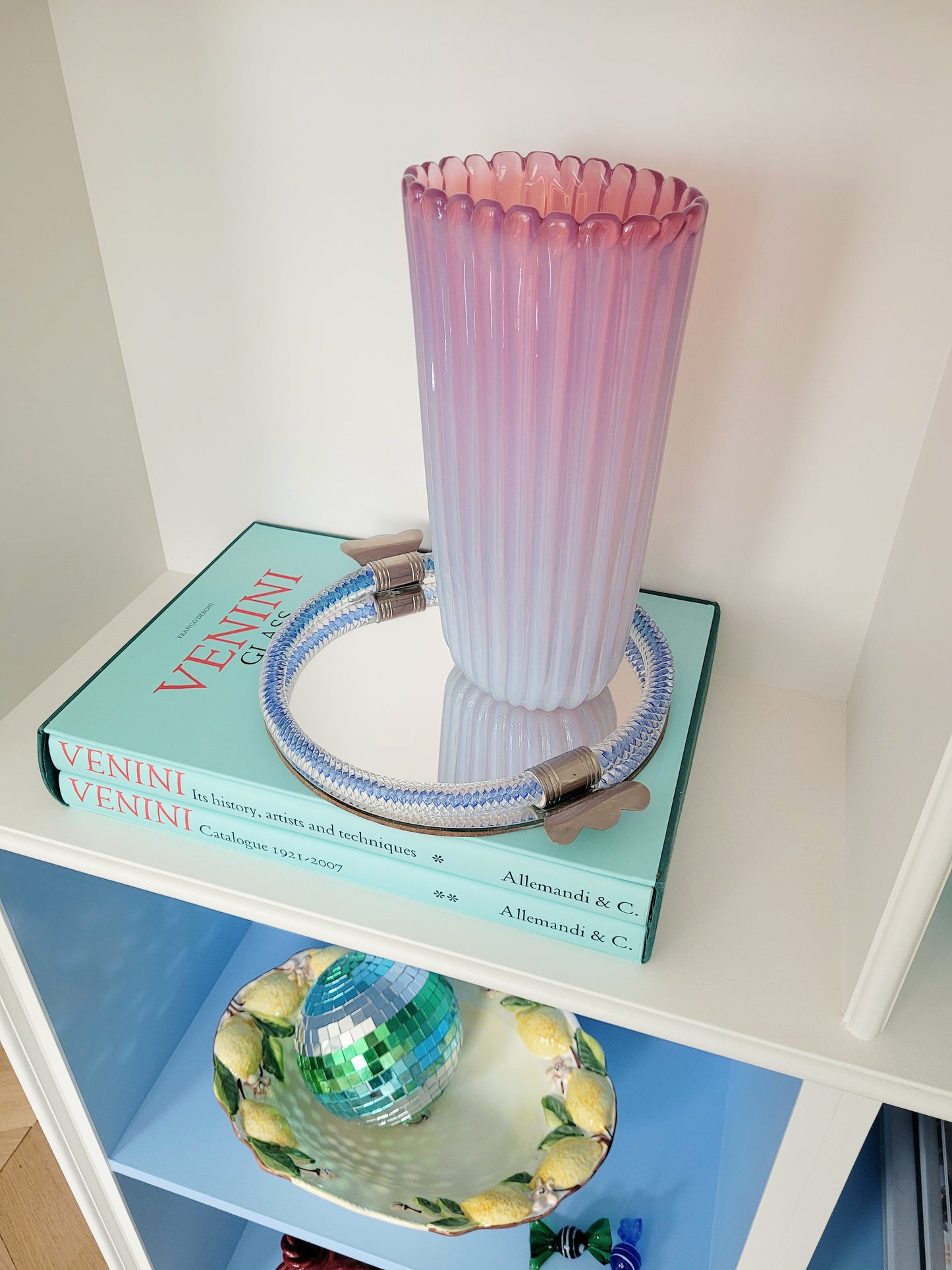 a large vintage pink ribbed Murano vase on a vintage Murano mirror tray and a stack of Venini books