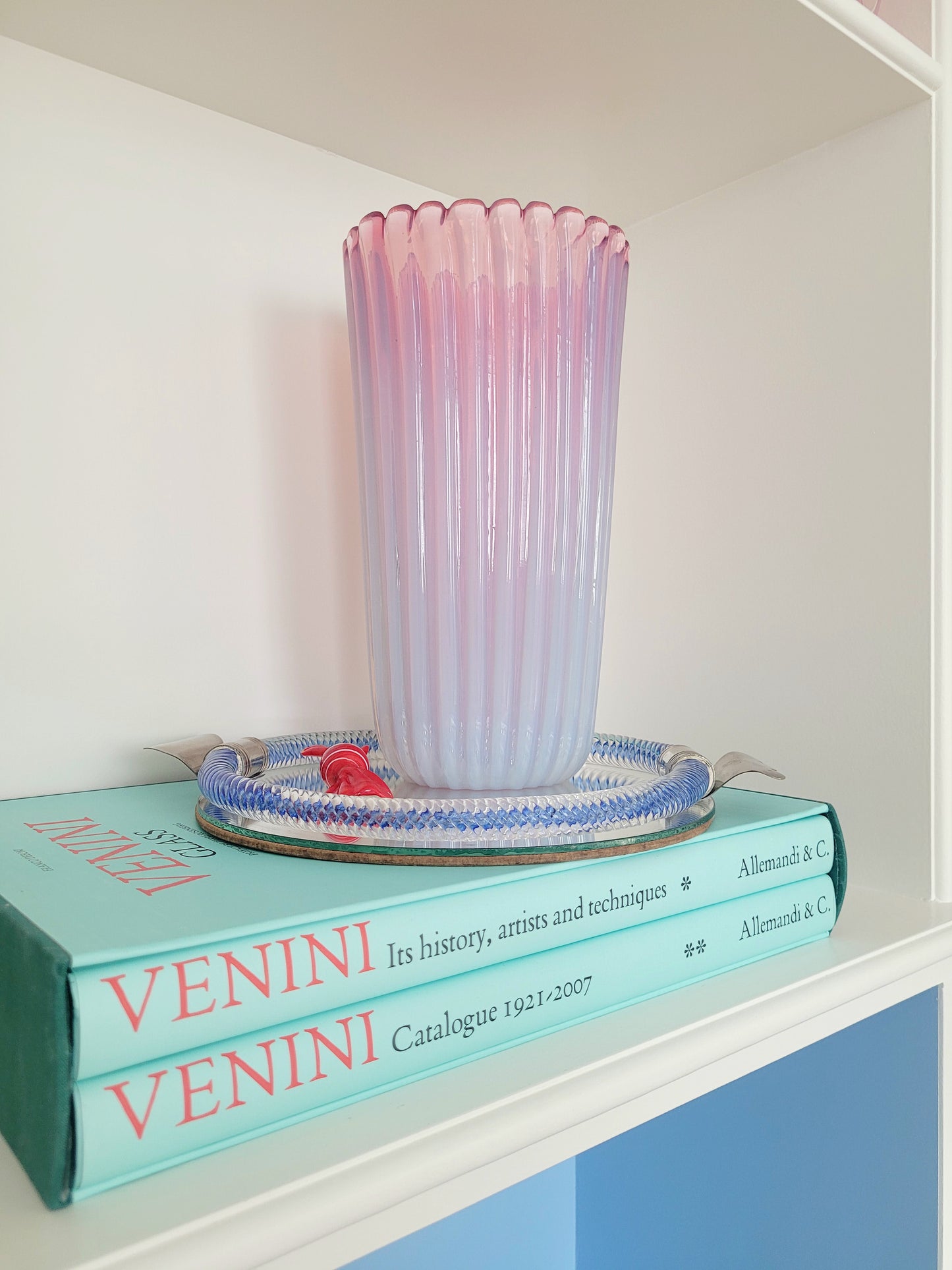 a large vintage pink ribbed Murano vase on a vintage Murano mirror tray and a stack of Venini books