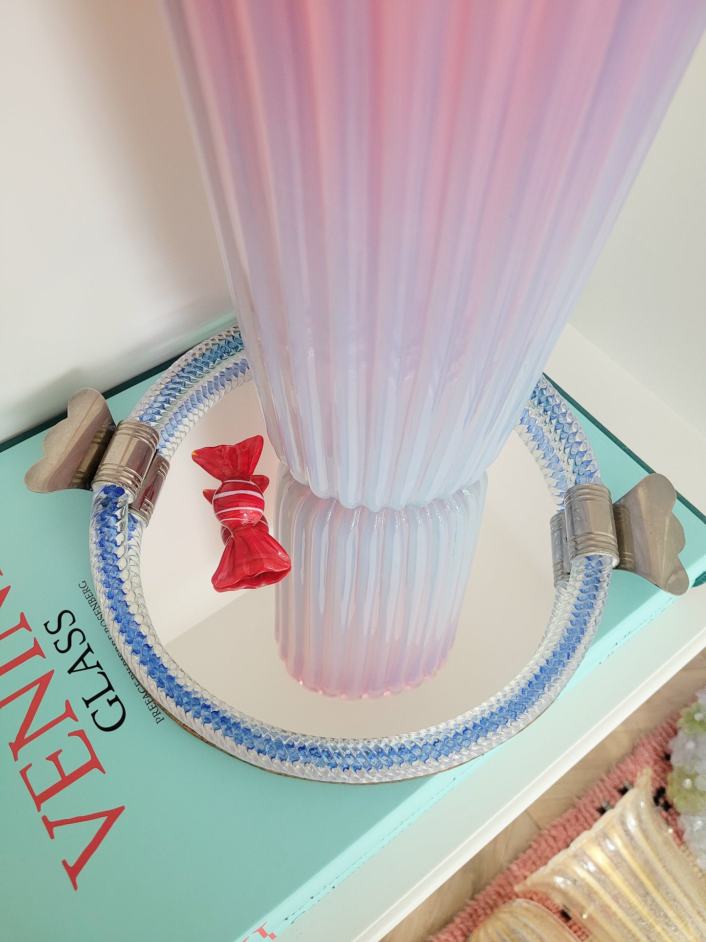 detail of a large vintage pink ribbed Murano vase on a vintage Murano mirror tray and a stack of Venini books
