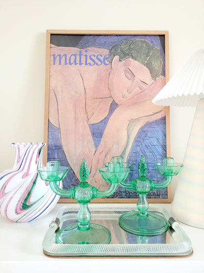A pair of light green Murano glass candle holders, attributed to Vittorio Zecchin, renowned Italian artist on a vintage Murano mirror tray and with a Murano vase in the back and a framed Matisse poster.
