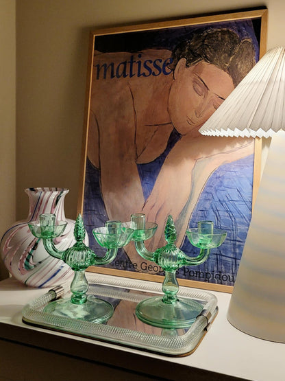 A pair of light green Murano glass candle holders, attributed to Vittorio Zecchin, renowned Italian artist on a vintage Murano mirror tray and with a Murano vase in the back and a framed Matisse poster.