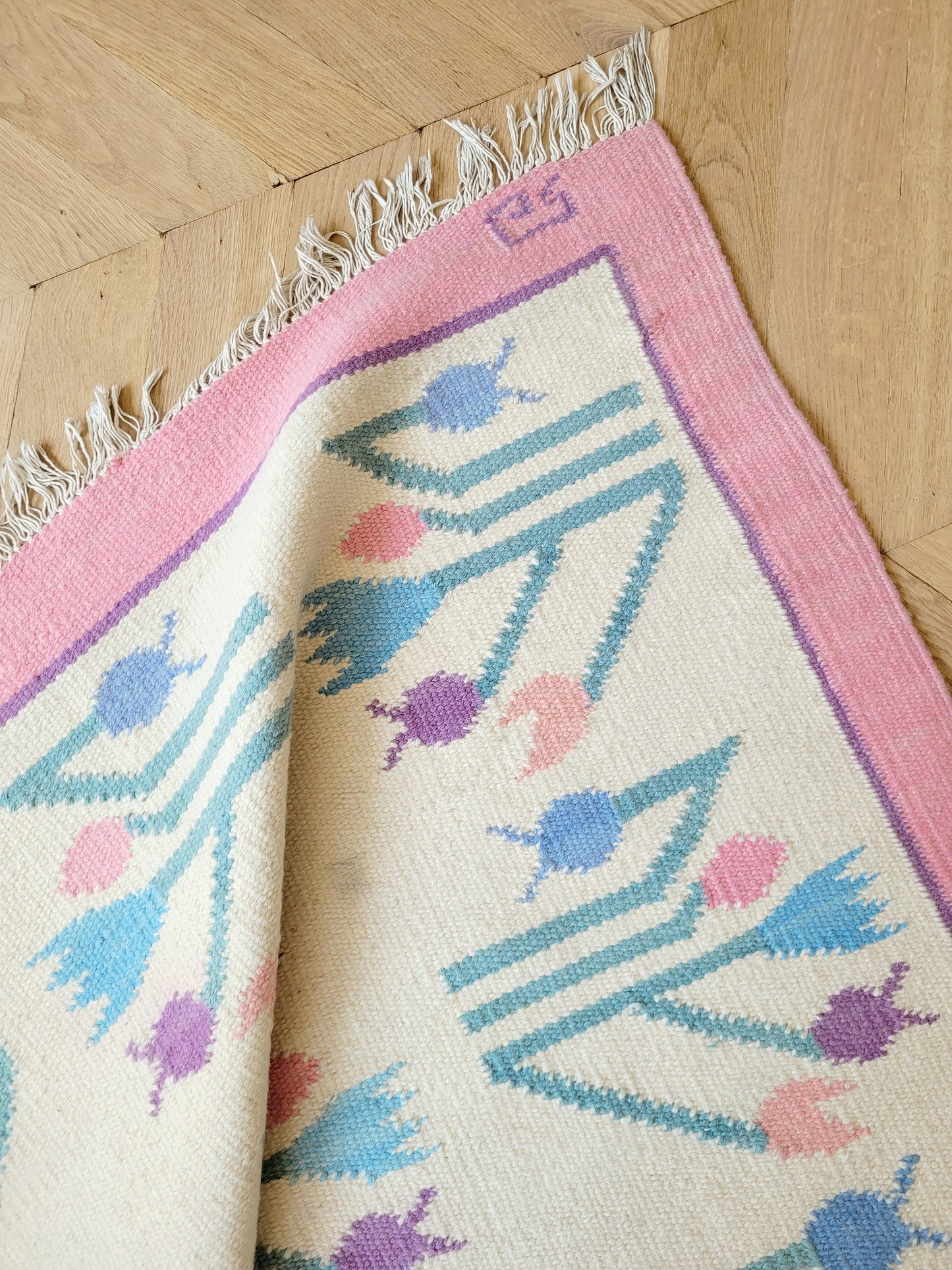 detailed top view of a pink and pastel coloured vintage rug with floral pattern