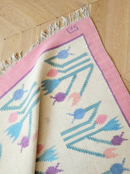 detailed top view of a pink and pastel coloured vintage rug with floral pattern