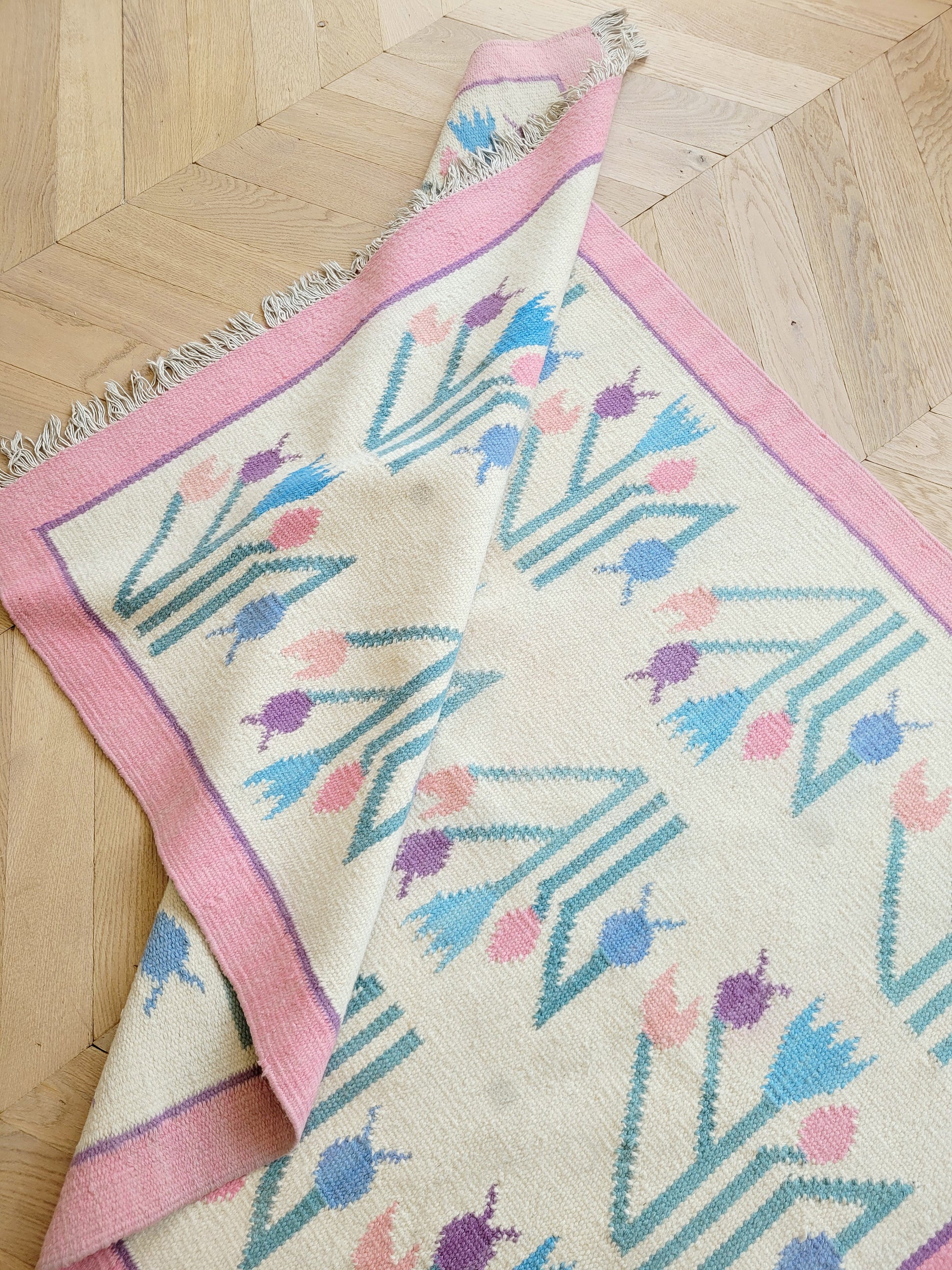 top view of a pink and pastel coloured vintage rug with floral pattern