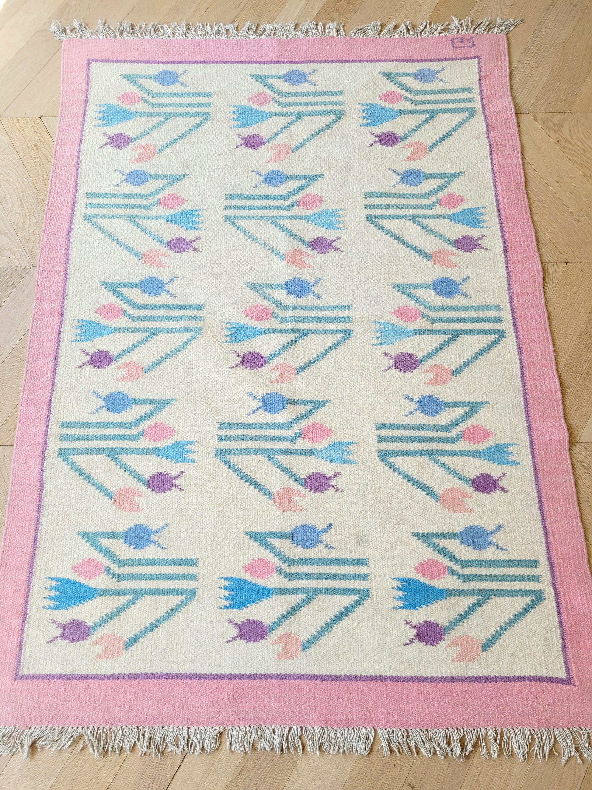 full top view of a pink and pastel coloured vintage rug with floral pattern