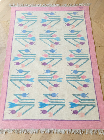 full top view of a pink and pastel coloured vintage rug with floral pattern
