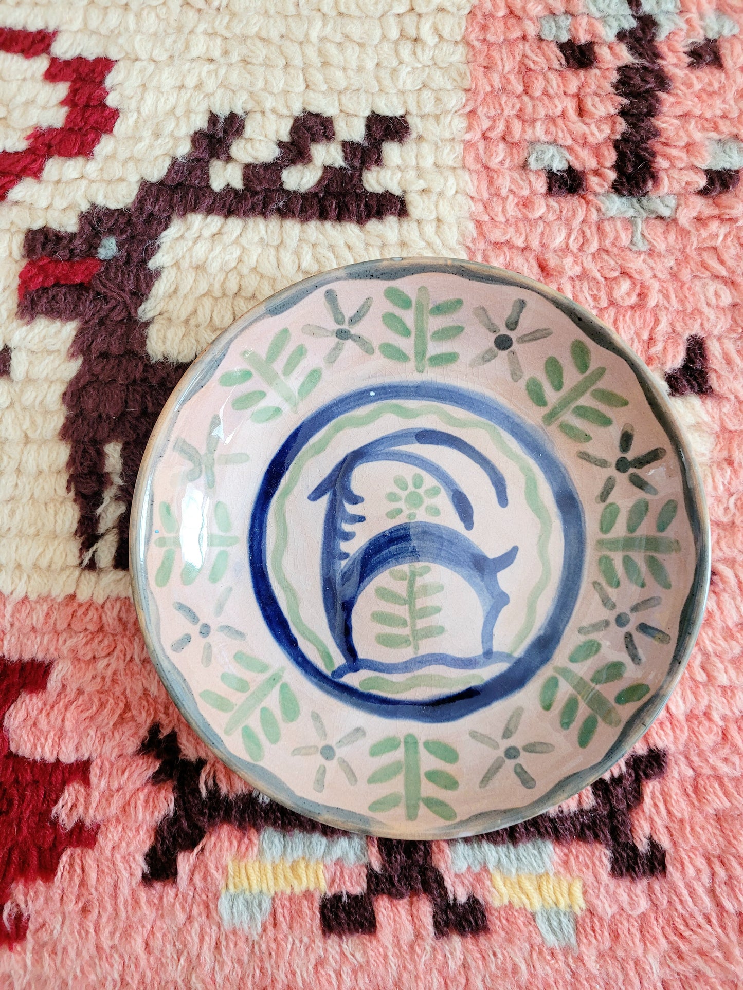 small French wall plate depicting a doe and made by François Miro for Sant Vicens Ceramics, Perpignan, France. Blue and green colours. The plate is on a colourful rug.