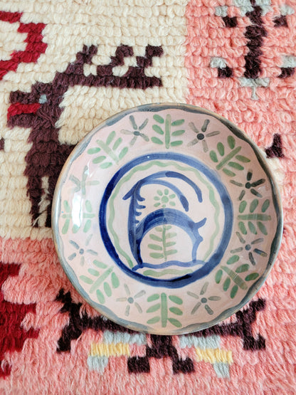 small French wall plate depicting a doe and made by François Miro for Sant Vicens Ceramics, Perpignan, France. Blue and green colours. The plate is on a colourful rug.
