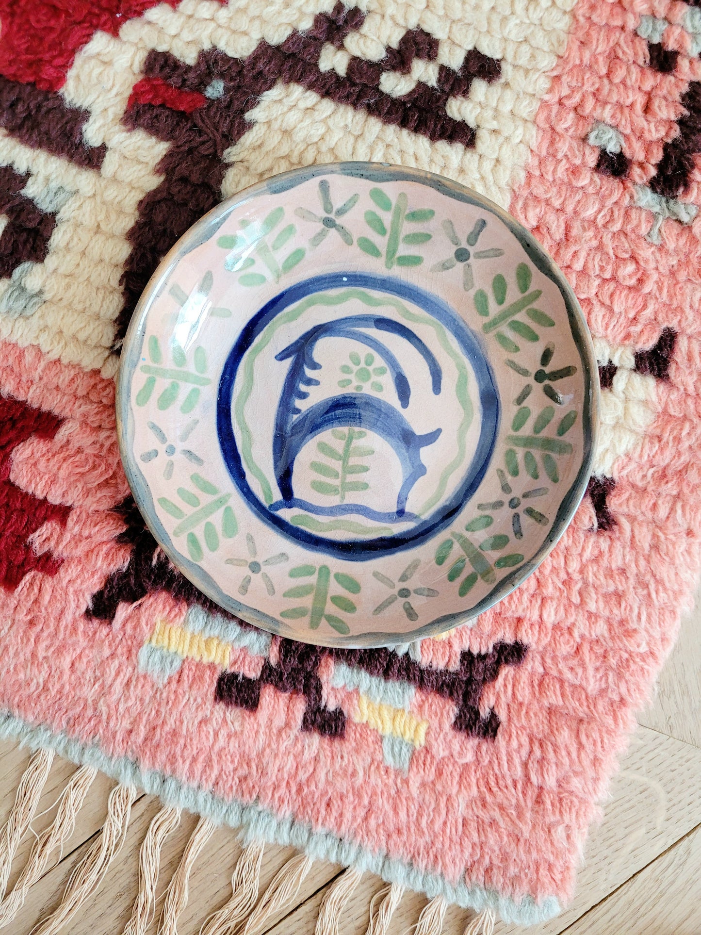 small French wall plate depicting a doe and made by François Miro for Sant Vicens Ceramics, Perpignan, France. Blue and green colours. The plate is on a colourful rug.