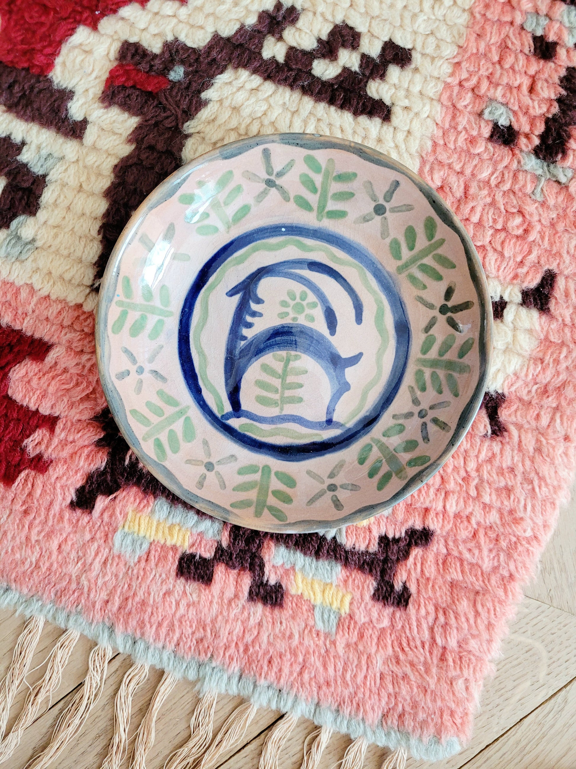 small French wall plate depicting a doe and made by François Miro for Sant Vicens Ceramics, Perpignan, France. Blue and green colours. The plate is on a colourful rug.