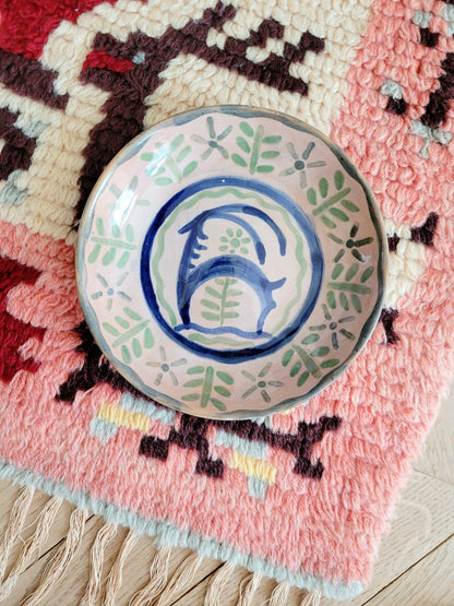 small French wall plate depicting a doe and made by François Miro for Sant Vicens Ceramics, Perpignan, France. Blue and green colours. The plate is on a colourful rug.