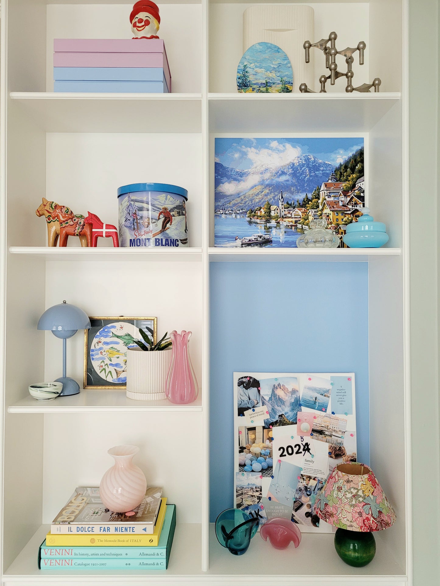 a vintage Murano pink swirl vase on a stack of colourful books in a built-in cabinet with vintage home decor