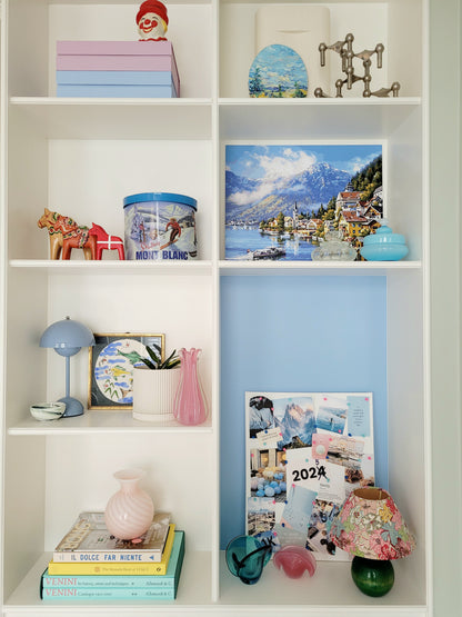 a vintage Murano pink swirl vase on a stack of colourful books in a built-in cabinet with vintage home decor