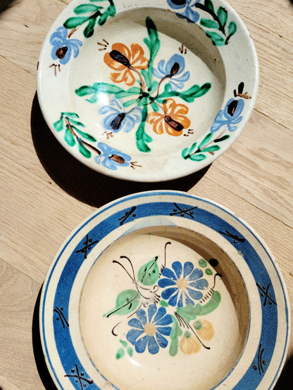 detail of two vintage hand-painted earthenware wall plates/bowls from Romania-Hungary with floral design on a parquet floor, typical folk art
