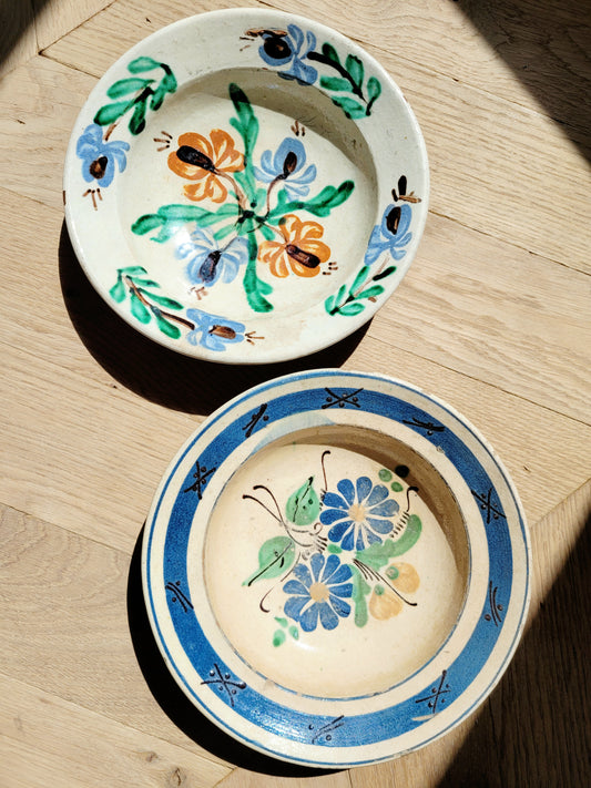 two vintage hand-painted earthenware wall plates/bowls from Romania-Hungary with floral design on a parquet floor, typical folk art