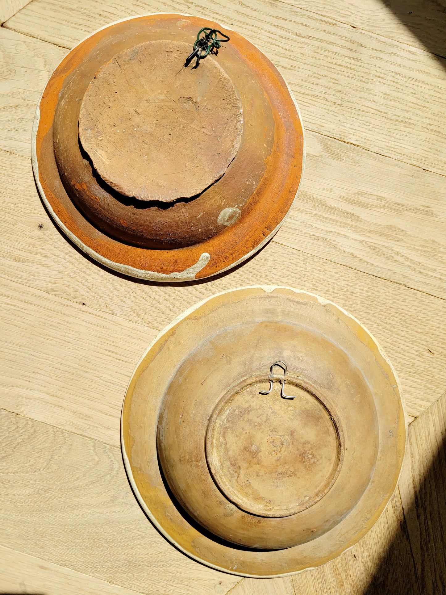 back view of two vintage hand-painted earthenware wall plates/bowls from Romania-Hungary with floral design on a parquet floor, typical folk art