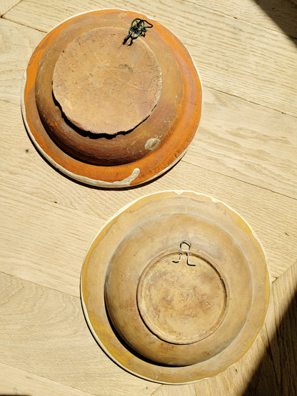 back view of two vintage hand-painted earthenware wall plates/bowls from Romania-Hungary with floral design on a parquet floor, typical folk art