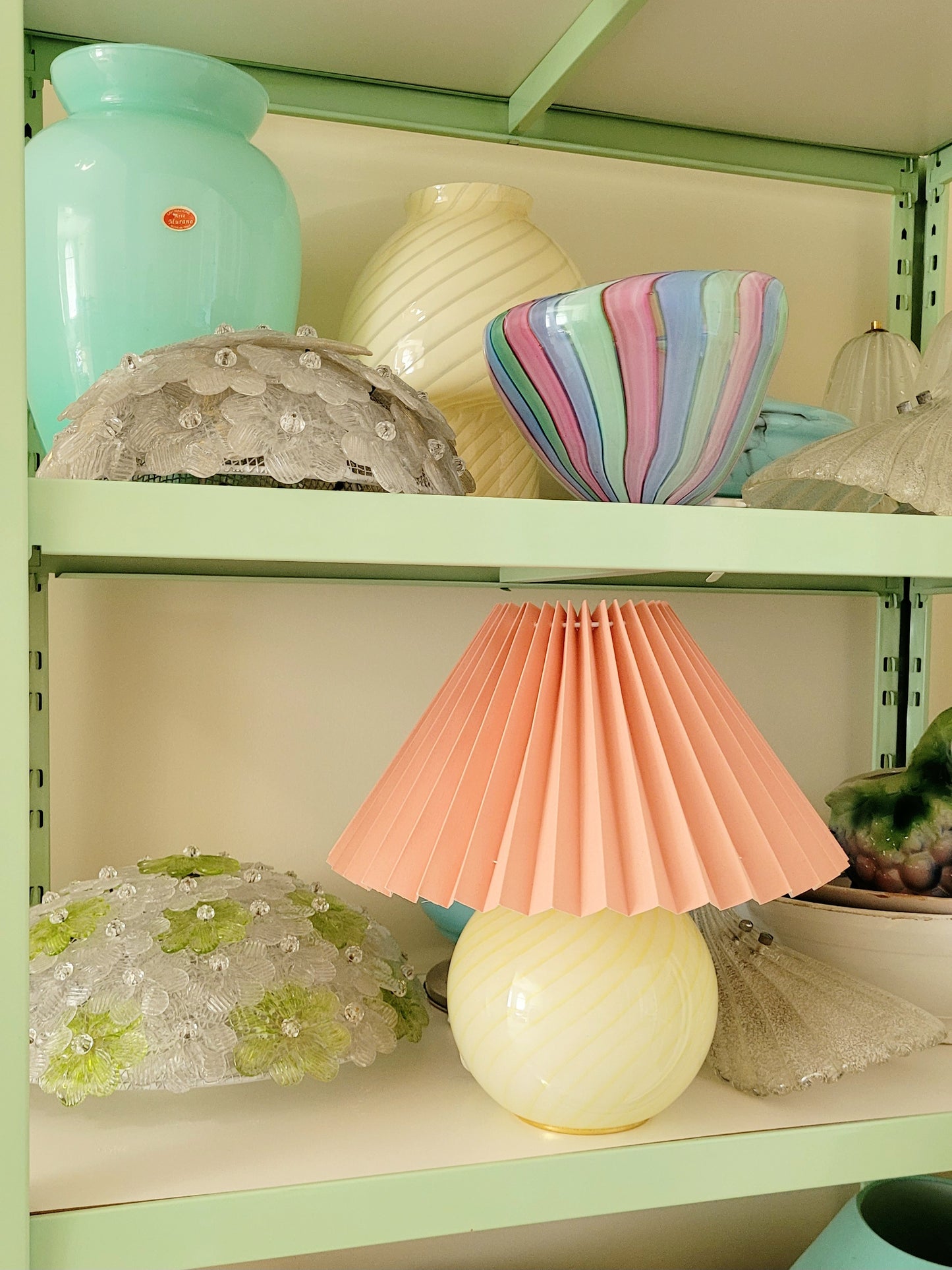 full view of a yellow swirl Murano table lamp, topped with a coral pleated shade