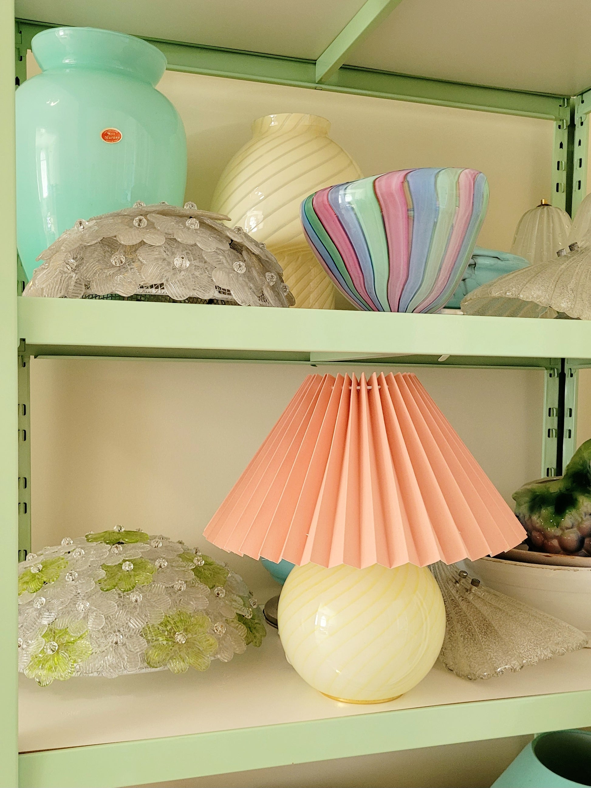 full view of a yellow swirl Murano table lamp, topped with a coral pleated shade