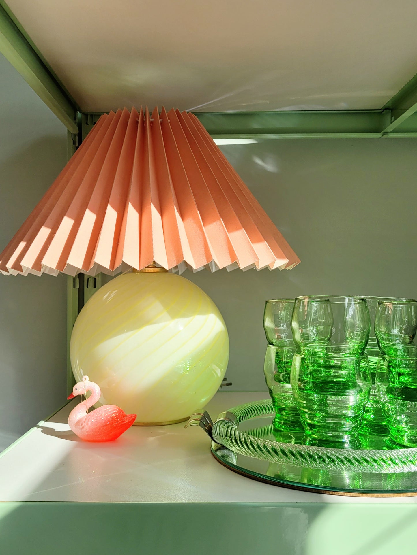 full view of a yellow swirl Murano table lamp, topped with a coral pleated shade